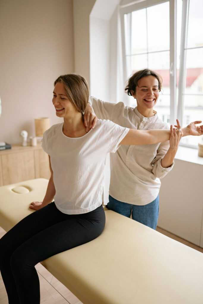 pexels photo 5793798 5793798 A therapist guides a woman in a stretching exercise on a massage table in a clinic setting.